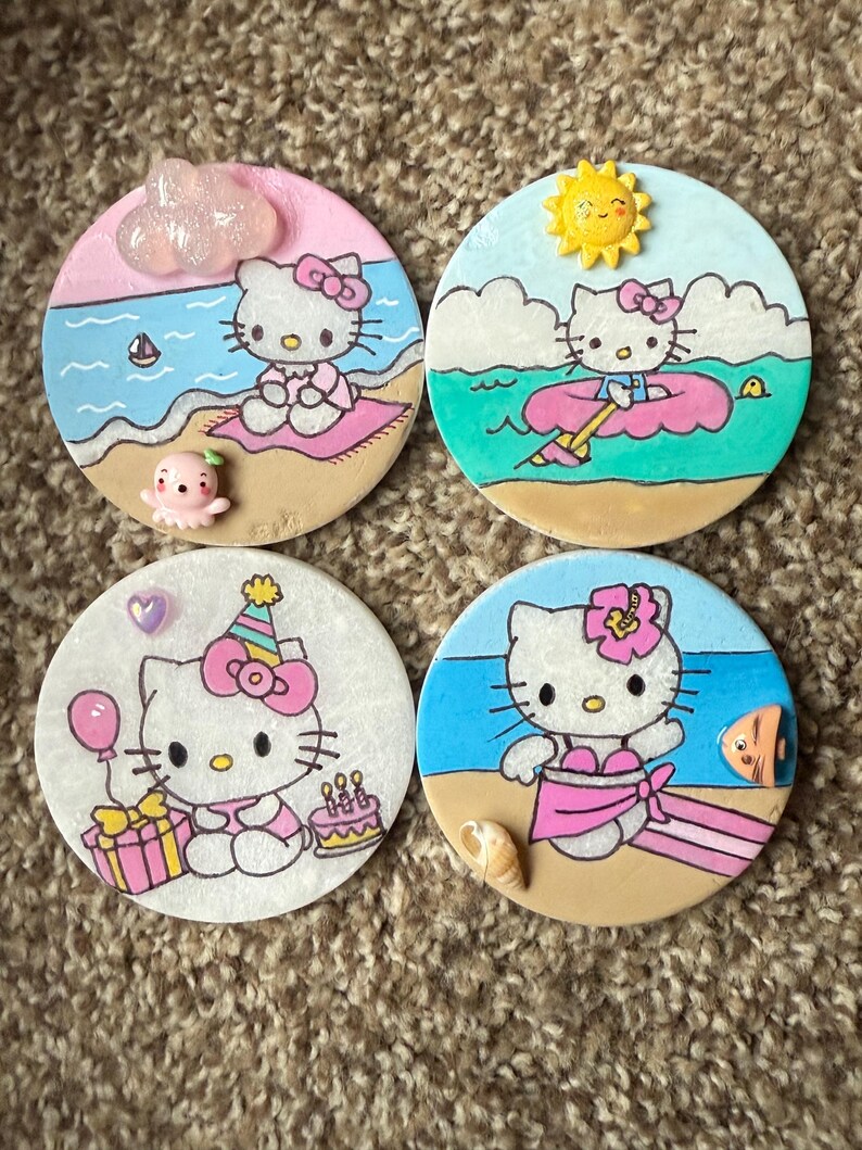 Op de afbeelding: Vier ronde keramische onderzetters met Hello Kitty in verschillende zomerse sc&egrave;nes. De onderzetters zijn geschilderd met Hello Kitty in een badpak, een zwemband, een verjaardagshoed en een wolk. Elke onderzetter heeft een andere achtergrondkleur en bevat andere zomerse details.