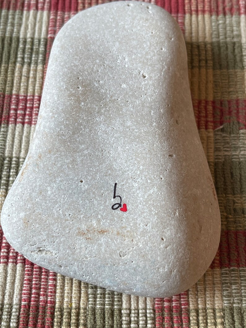 Puede incluir: Una piedra gris con una nota musical negra y un coraz&oacute;n rojo pintado en ella.