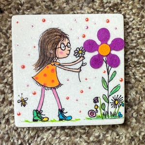Puede incluir: Una ilustraci&oacute;n caprichosa en un cuadrado blanco representa a una ni&ntilde;a con gafas con un vestido naranja, recogiendo una flor. Tambi&eacute;n se presenta una gran flor de fieltro p&uacute;rpura y una abeja. Los puntos rojos y naranjas a&ntilde;aden un toque l&uacute;dico.