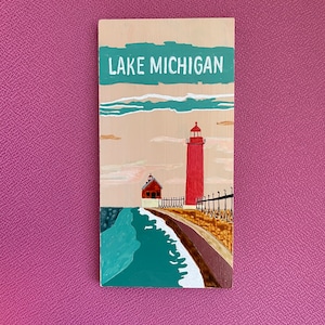 K&ouml;nnte beinhalten: Ein Holzschild mit einem gemalten Bild eines roten Leuchtturms auf einem See mit dem Text "LAKE MICHIGAN" oben.