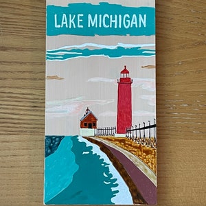 K&ouml;nnte beinhalten: Ein Holzschild mit einer gemalten Szene eines roten Leuchtturms auf einem Pier mit einem blauen See und wei&szlig;en Wolken. Das Schild tr&auml;gt die Aufschrift "LAKE MICHIGAN" in wei&szlig;en Buchstaben.