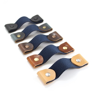 May include: Five leather and canvas straps with metal button closures. The straps are in various colors, including black, blue, brown, and tan.