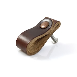 May include: A brown leather cabinet pull with a copper-colored knob and a silver screw.