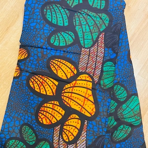 May include: A colourful fabric with a striking pattern. The design showcases large, stylized floral shapes in yellow, green, and black against a blue backdrop. The fabric has a textured appearance, suggesting a woven material.