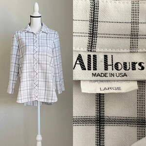 Puede incluir: Camisa de botones de manga larga a cuadros blancos y negros. La camisa tiene una etiqueta que dice "All Hours Made in USA Large".