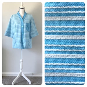 May include: A light blue and white striped shirt with a collar and three buttons. The shirt has two pockets on the front and short sleeves.