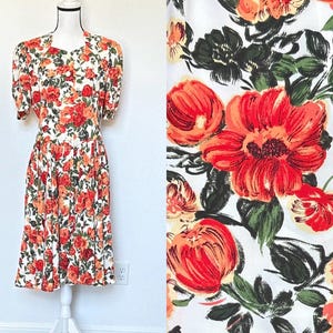 May include: A white dress with a red and orange floral print. The dress has a short sleeve and a fitted bodice. The skirt is full and flows out from the waist.