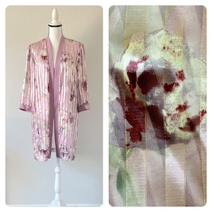 May include: A pink and white floral patterned robe with a striped design. The robe has long sleeves and a shawl collar.