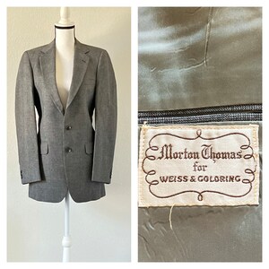 Op de afbeelding: Een grijs wollen blazer met een knoopsluiting met twee knopen en een label met de tekst "Morton Thomas for Weiss & Goldring".