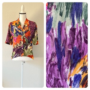 May include: A cropped, short-sleeved button-up shirt with a colorful abstract floral print in shades of purple, orange, green, and yellow.