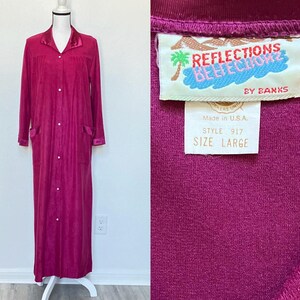Könnte beinhalten: Langer, magentafarbener Bademantel mit Satin-Kragen und Manschetten, mit Knopfleiste und zwei Vordertaschen. Der Bademantel wird auf einer Schaufensterpuppe präsentiert. Das Etikett lautet "REFLECTIONS BY BANKS" und "GRÖSSE LARGE".