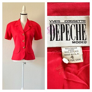 Op de afbeelding: Een rode blazer met korte mouwen, gouden knopen en een getailleerde pasvorm. De blazer heeft een reverskraag en twee decoratieve zakken. Het label luidt "YVES COSSETTE DEPECHE MODE". Maat 4, gemaakt in de VS.