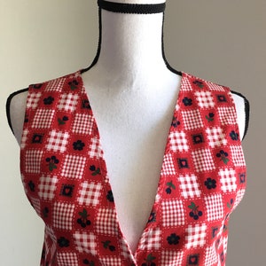May include: A red and white gingham sleeveless vest with a deep V-neck and a floral pattern.