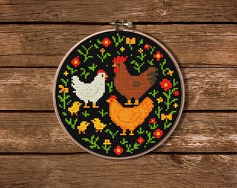 May include: A cross-stitch embroidery hoop featuring a black background with a design of chickens and chicks. The chickens are white, brown, and orange, surrounded by red and yellow flowers and green foliage. The hoop is held in a wooden frame.