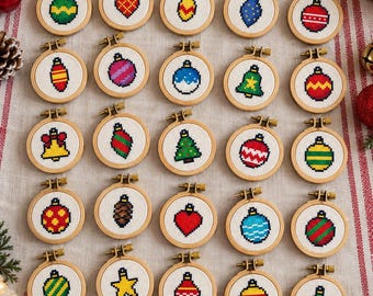 May include: A collection of twenty-five small circular wooden embroidery hoops, each containing a unique cross-stitch design of a Christmas ornament, including various shapes like spheres, bells, stars, and hearts in vibrant colors on white fabric.