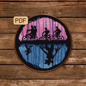 May include: A cross-stitch pattern featuring a silhouette of four figures riding bicycles in a pink and purple forest, with a shadowy figure emerging from the ground below. The pattern is framed in a black hoop and includes the text "Alton Embroidery".