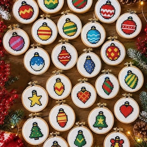 May include: A collection of twenty-five small circular wooden embroidery hoops, each containing a unique cross-stitch design of a Christmas ornament, including various shapes like spheres, hearts, bells, and trees in red, green, blue, and yellow.