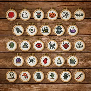 May include: A collection of twenty-four small, round cross-stitch embroidery hoops with Halloween-themed designs. Each hoop features a different spooky image, including a ghost, pumpkin, and black cat, set against a wooden background.