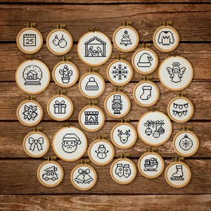 May include: A collection of twenty-eight circular wooden embroidery hoops containing white fabric with black cross-stitch designs of various Christmas icons, including a calendar, ornaments, a nativity scene, a tree, a sweater, and Santa Claus.