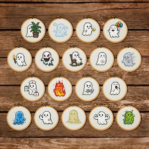 May include: A collection of nineteen circular wooden embroidery hoops, each containing a unique pixel art ghost design stitched on white fabric. The ghosts feature various expressions, colors, and accessories, including a plant, balloons, a torch, and fire.