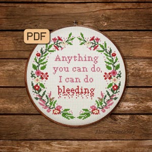 Peut inclure: Un cerceau de broderie blanc avec une bordure de couronne florale. Le cerceau présente le texte "Anything you can do, I can do bleeding" en lettres roses.