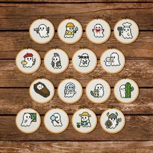 May include: A collection of 15 small, round cross-stitch hoops featuring cartoon ghosts in various costumes and professions. The ghosts are depicted as a construction worker, chef, artist, ninja, and more. The hoops are set against a wooden background.