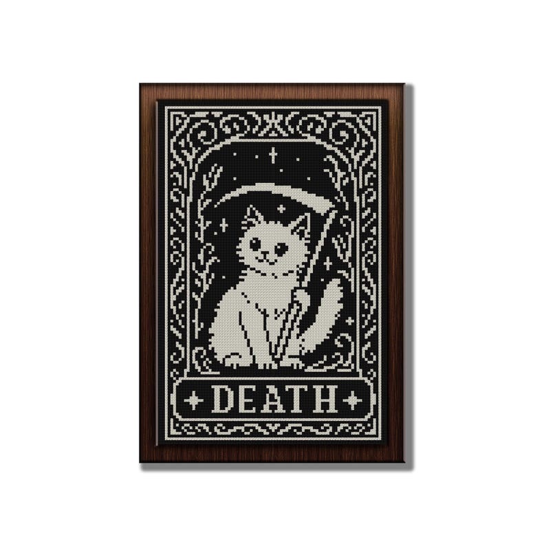 May include: A framed cross-stitch embroidery featuring a white cat holding a scythe, set against a black background with white stars and floral borders. The word DEATH is printed in white capital letters within a rectangular banner at the bottom.