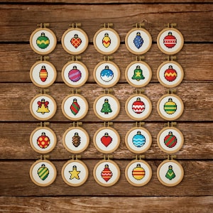 May include: A collection of 24 small, round cross-stitch ornaments in wooden hoops, each featuring a different Christmas-themed design. The designs include ornaments, bells, and trees in various colors, set against a wooden background.