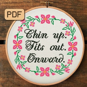 Puede incluir: Un aro de bordado blanco con un borde floral y el texto "Chin up.  Tits out.  Onward." en letras negras.