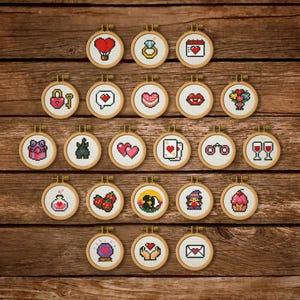 Peut inclure: Une collection de petits cercles à broder ronds avec divers motifs de point de croix sur le thème de la Saint-Valentin. Les motifs comprennent des cœurs, des bagues, des fleurs et d'autres symboles romantiques. Les cercles sont disposés sur une surface en bois.