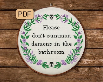 May include: A white embroidery hoop with a floral wreath design and the text "Please don't summon demons in the bathroom".