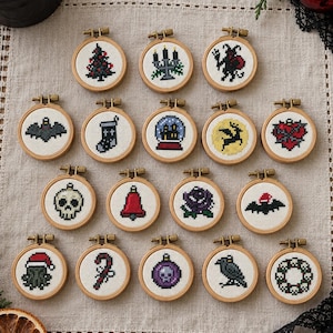 Könnte beinhalten: Eine Sammlung von neunzehn kleinen runden Stickrahmen aus Holz, die jeweils ein einzigartiges Kreuzstichmotiv mit weihnachtlichen und gotischen Elementen wie einem Totenkopf, einer Fledermaus, einem Raben, einem Weihnachtsbaum und einem Kranz zeigen.