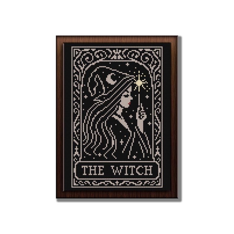 May include: Cross-stitch art of a witch with long hair, a hat, and a wand, set against a black background. The image is framed in a dark wood frame, with the words "THE WITCH" at the bottom.
