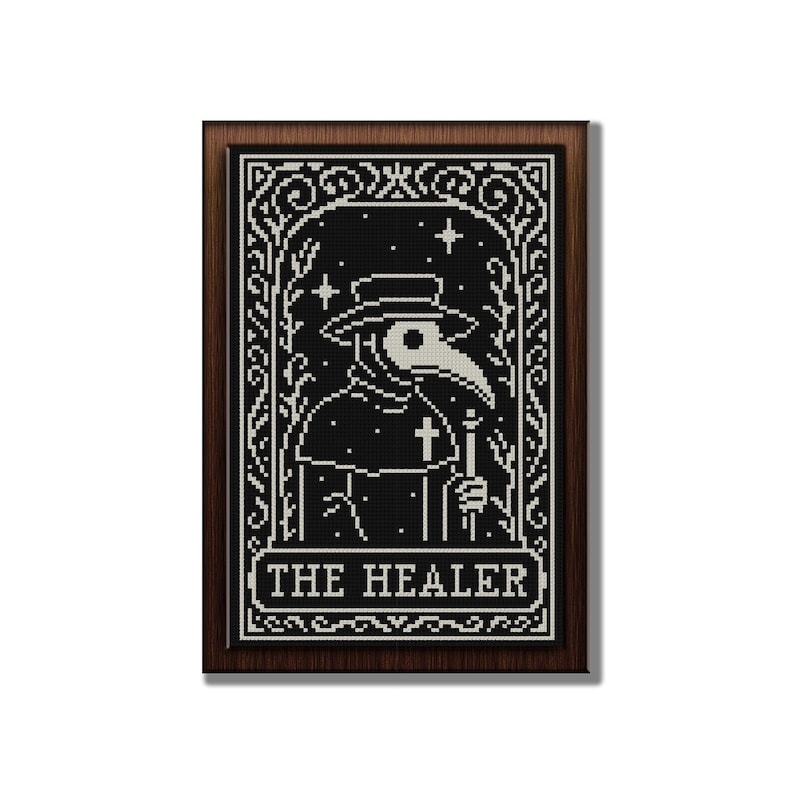 May include: A framed, black and white cross-stitch design featuring a plague doctor with a long beak, hat, and cross. The text "THE HEALER" is at the bottom. The frame is a dark brown color.