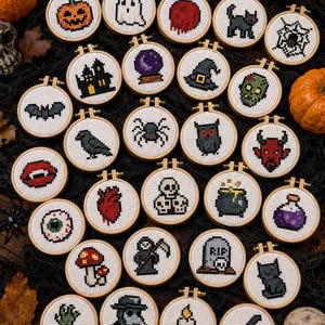 May include: A collection of small, round cross-stitch embroidery hoops with Halloween-themed designs. The designs include a jack-o'-lantern, ghost, spiderweb, black cat, haunted house, and more. The hoops are arranged on a dark surface.