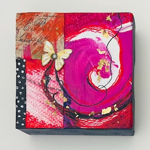 May include: A mixed media art piece featuring a gold butterfly and abstract design. The artwork incorporates red, pink, and black colors with gold leaf accents. The piece has a black border and a collage of textures.