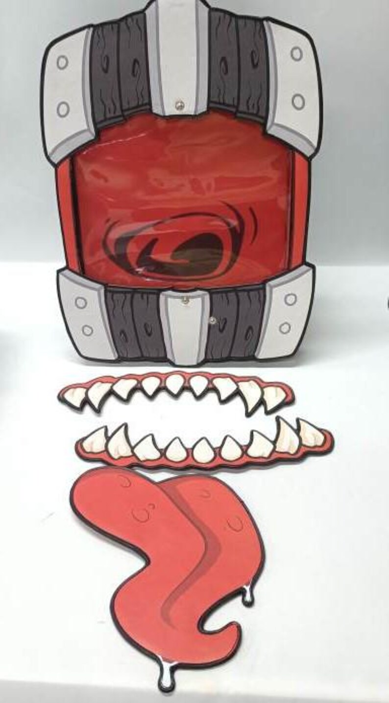 Puede incluir: Un accesorio de boca rojo y caricaturesco con una ventana de pl&aacute;stico transparente, detalles grises y blancos y paneles con aspecto de madera. Incluye dientes de cart&oacute;n separados y una lengua roja con detalles goteantes. Ideal para Halloween o uso teatral.