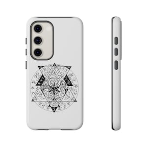 May include: White phone case featuring a black geometric design with intricate symbols and text. The design includes triangles, circles, and a central floral-like pattern. The phone case has a black border and camera housing.