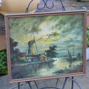 May include: A framed painting of a windmill on a lake with a sailboat in the distance. The sky is a mix of blue, gray, and yellow with fluffy clouds. The painting is in a brown frame.