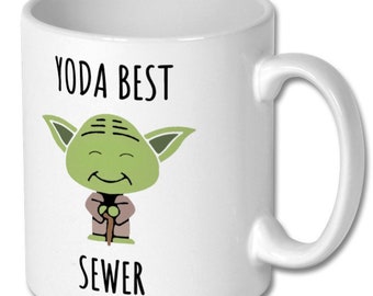 Może przedstawiać: Biały kubek ceramiczny z zielonym rysunkowym postacią Yody i tekstem "YODA BEST SEWER".