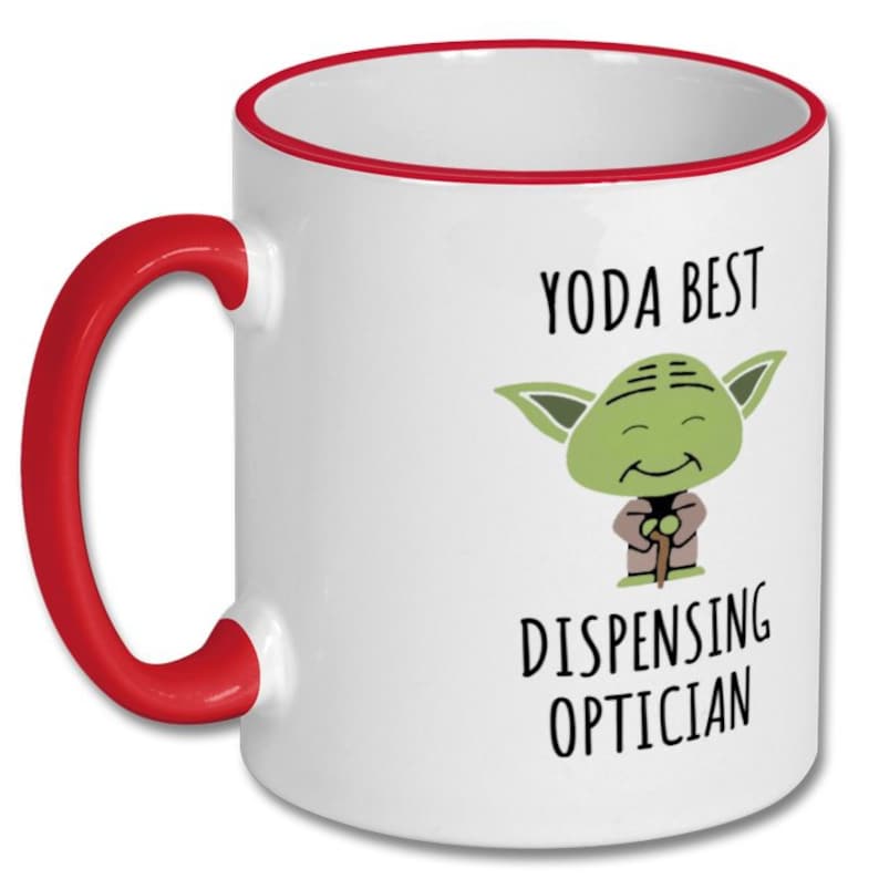 May include: White ceramic mug with a red rim and handle. The mug features a cartoon image of Yoda with the text "Yoda Best Dispensing Optician".