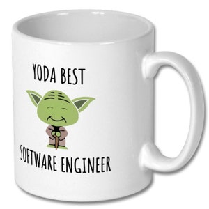 May include: White ceramic mug with a green cartoon character of Yoda holding a stick. The text "Yoda Best Software Engineer" is printed on the mug.