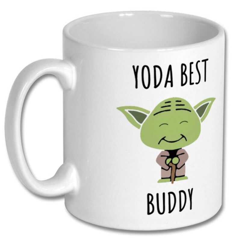 May include: White ceramic coffee mug with a green cartoon Yoda character holding a stick. The text "YODA BEST BUDDY" is printed on the mug.