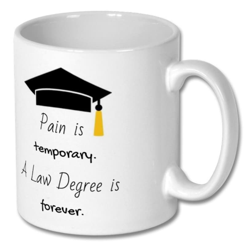 May include: White ceramic mug with a black graduation cap graphic and the text "Pain is temporary. A Law Degree is forever." The mug has a curved handle and is suitable for hot or cold beverages.