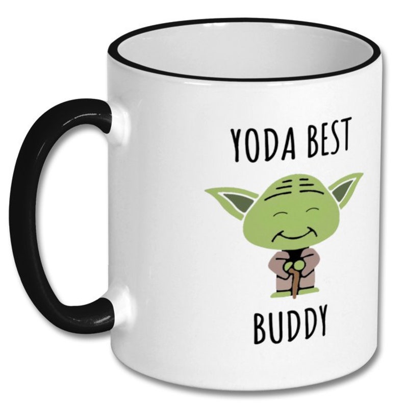 May include: White ceramic coffee mug with a black rim and handle. The mug features a cartoon image of Yoda from Star Wars with the text "Yoda Best Buddy".