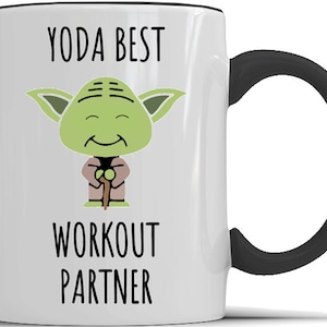 May include: White ceramic mug with a black handle. The mug features a cartoon image of Yoda from Star Wars with the text "YODA BEST WORKOUT PARTNER".