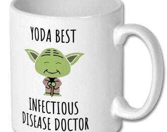 Może przedstawiać: Biały kubek ceramiczny z ilustracją zielonej postaci Yody. Na kubku nadrukowany jest tekst "Yoda Best Infectious Disease Doctor".