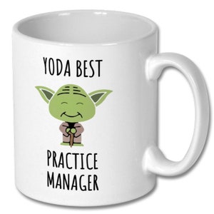 May include: White ceramic mug with a green cartoon character of Yoda from Star Wars. The mug has the text "Yoda Best Practice Manager" printed on it.