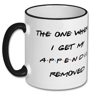 May include: White ceramic coffee mug with a black rim and handle. The mug has a black and white graphic that says "The One Where I Get My Appendix Removed" with a colorful dot pattern.