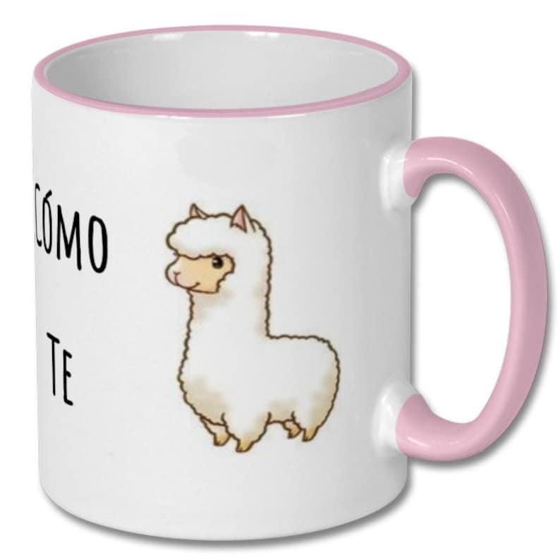 May include: White ceramic coffee mug with a pink rim and handle. The mug features a cartoon illustration of a white llama with the text "C&oacute;mo te" printed on the front.
